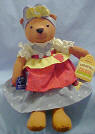 Country Cousins Bear - This adorable plush Country Cousin Bear is wearing a slate and cream colored dress with a red and yellow apron. She also has cream colored pantaloons. There are coordinating patches and buttons sewn on and macrame belts and ties. 15 inches