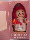 Happy Birthday Raggedy Ann Musical Plush Rag Doll - From the Raggedy Ann Collection. Raggedy Ann Happy Birthday Boxed Gift Doll. Raggedy Ann wears a&nbsp;multi&nbsp;color check dress with an apron&nbsp;that says "Happy birthday." Press her belly and hear "Happy Birthday To You." Comes in a gift box that opens at the front, with spaces to write in to/from. Measures 9" high.&nbsp; She is holding a plush gift in her hand. safe for ages over 3 