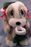 Christmas Sad Sam's Santa Elf Honey Basset Hound with Stocking - Honey is wearing a green velvety Elf hat with white faux fur trim and red bows on her ears.  She is holding a matching stocking which can be filled with goodies. (safe for ages over 3) 9 inches