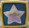 Gund Sesame Street Activity Block (click on the picture for a larger view)  Side 1 is Elmo - Unzip the zipper triangle to see a triangle MIRROR and the word 'triangle'.  Side 2 is Ernie with his Rubber Duckie (Duckie krinkles when you squeeze it) - Unvelcro the oval flap to find a leathery feeling oval shape&nbsp;and the word 'oval'.  Side 3 is Big Bird - Unbotton the buttoned triangle&nbsp;to find a laced platellet&nbsp;to learn how to tie your shoes and the word 'rectangle'.  Side 4 is Cookie Monster - Unvelcro the blue circle to find a cookie that krinkles and the word 'circle'.  Side 5 is Zoe - Unvelcro the orange square to find 2 square plastic toys and the word 'square'  Side 6 is a shiny Sesame Street star - Unvelcro the star to find the numbers 1, 2, 3, 4, and 5 and the word 'star'.  7 1/2 inch cube