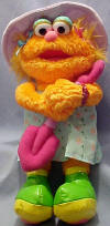 Gund Sesame Street Plush Gardener  Zoe - made from a soft plush fabric.  Zoe is wearing a flowered sundress, hot green shoes with pink hearts on the bottom, and a lilac velvety hat w flowers on it.  She is holding a shovel in her hands.  14 inches