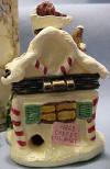 Back view of 1st Edition Boyds Uncle Beans Treasure Box Kringles Sweet Retreat with S. C. McNibble -(Introduced Fall 2002 and has been retired.) Inspired by Boyds' QVC exclusive Kringle's Village piece! This candy-coated Treasure Box is designed in the shape of a gingerbread house with all the trimmins. Pop the sparkly rooftop to find a lift out tray filled with hard candies. S.C. McNibble hides underneath, protectin' his stash of Christmas candies! Quote on bottom: "How sweet it is!" - Jackie Gleason 2 1/4 inches high by 1 3/4 inches wide